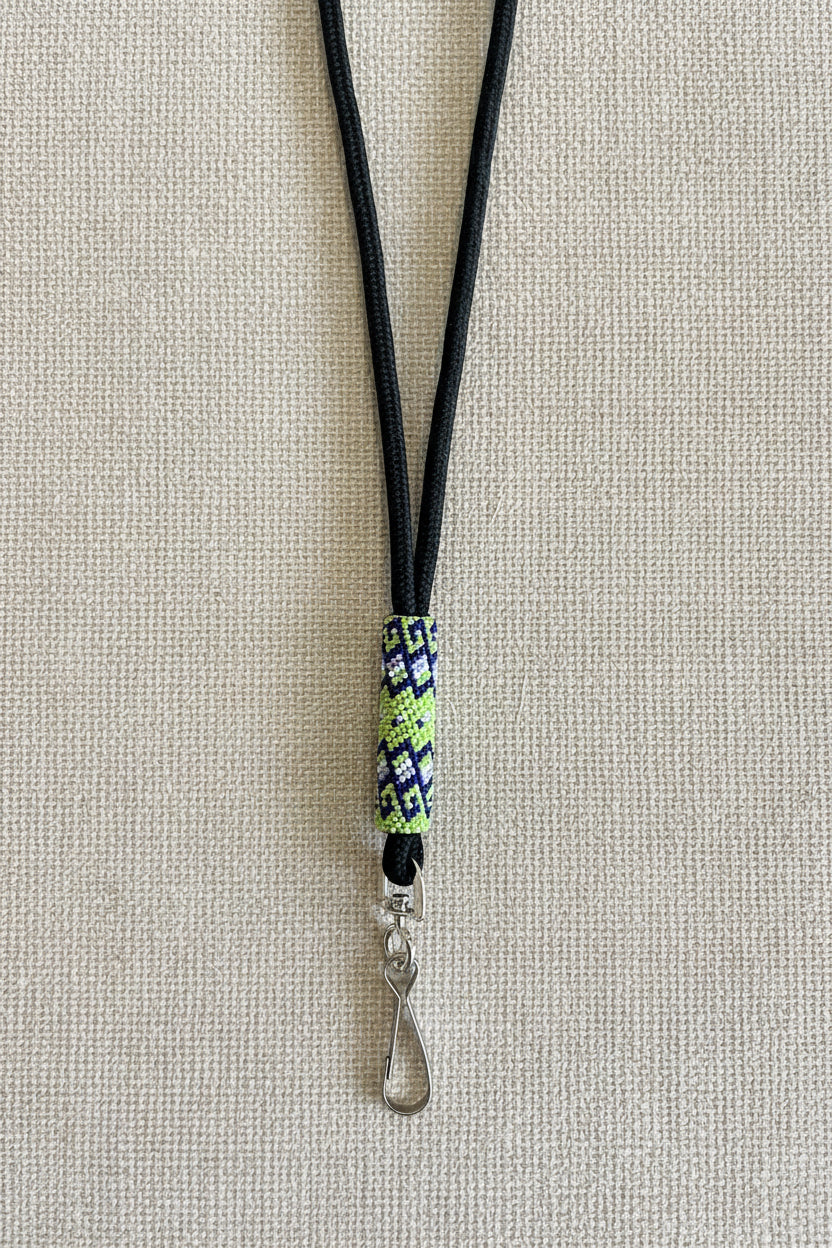 Black lanyard with a decorative charm on a beige fabric background