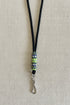 Black lanyard with a decorative charm on a beige fabric background